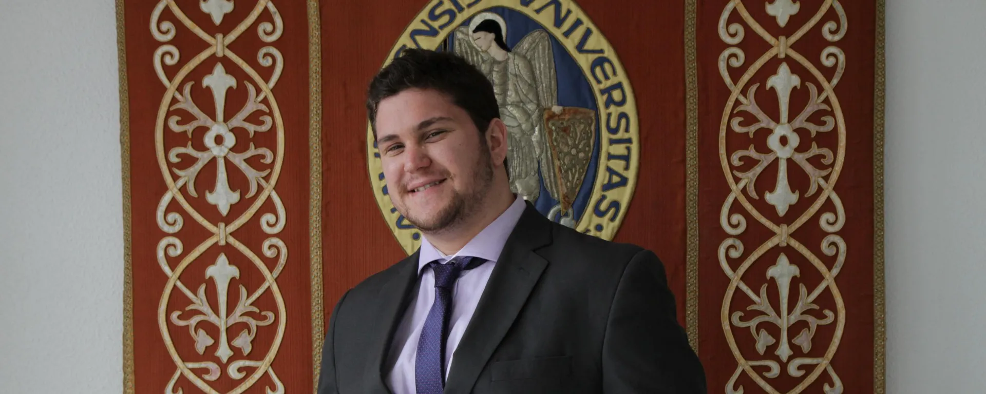 Daniel Jurburg frente al escudo de la Universidad de Navarra.