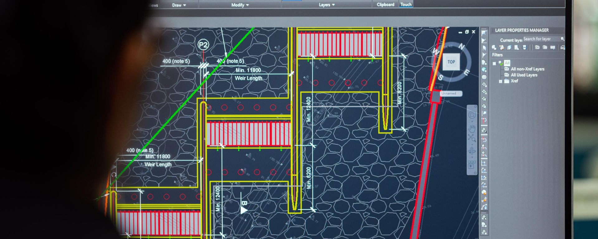 Un ingeniero mira a la pantalla de una computadora en la que aparece el plano de una obra.