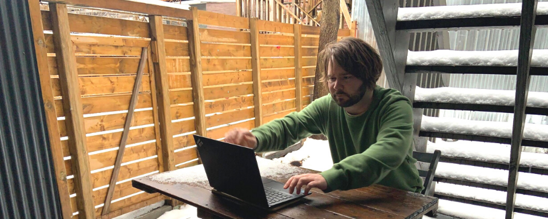 Olivier Vachon frente a una computadora en un jardín con nieve. 